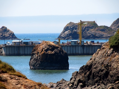 [Rocks in the bay near the port off-loading structures and equipment.]